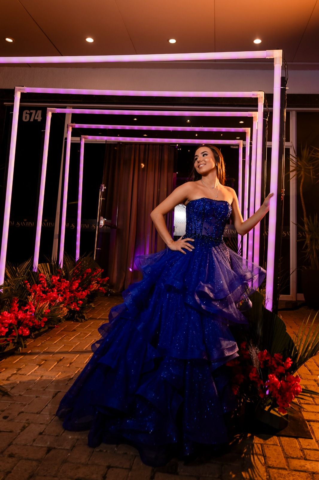 Debutante em vestido azul royal sob estrutura de luzes