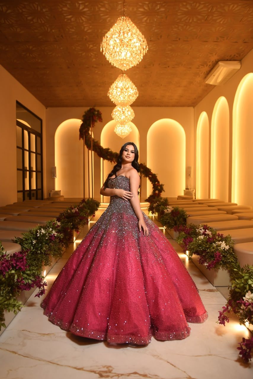 Debutante em vestido vermelho e prata sob lustres dourados